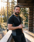Man in the black Shieldwall compression tee on a cabin porch with morning coffee