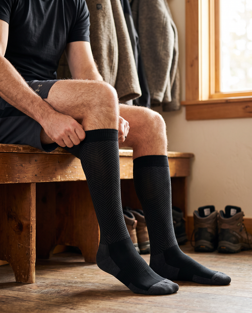 Man pulling up Longship compression socks on a cabin bench