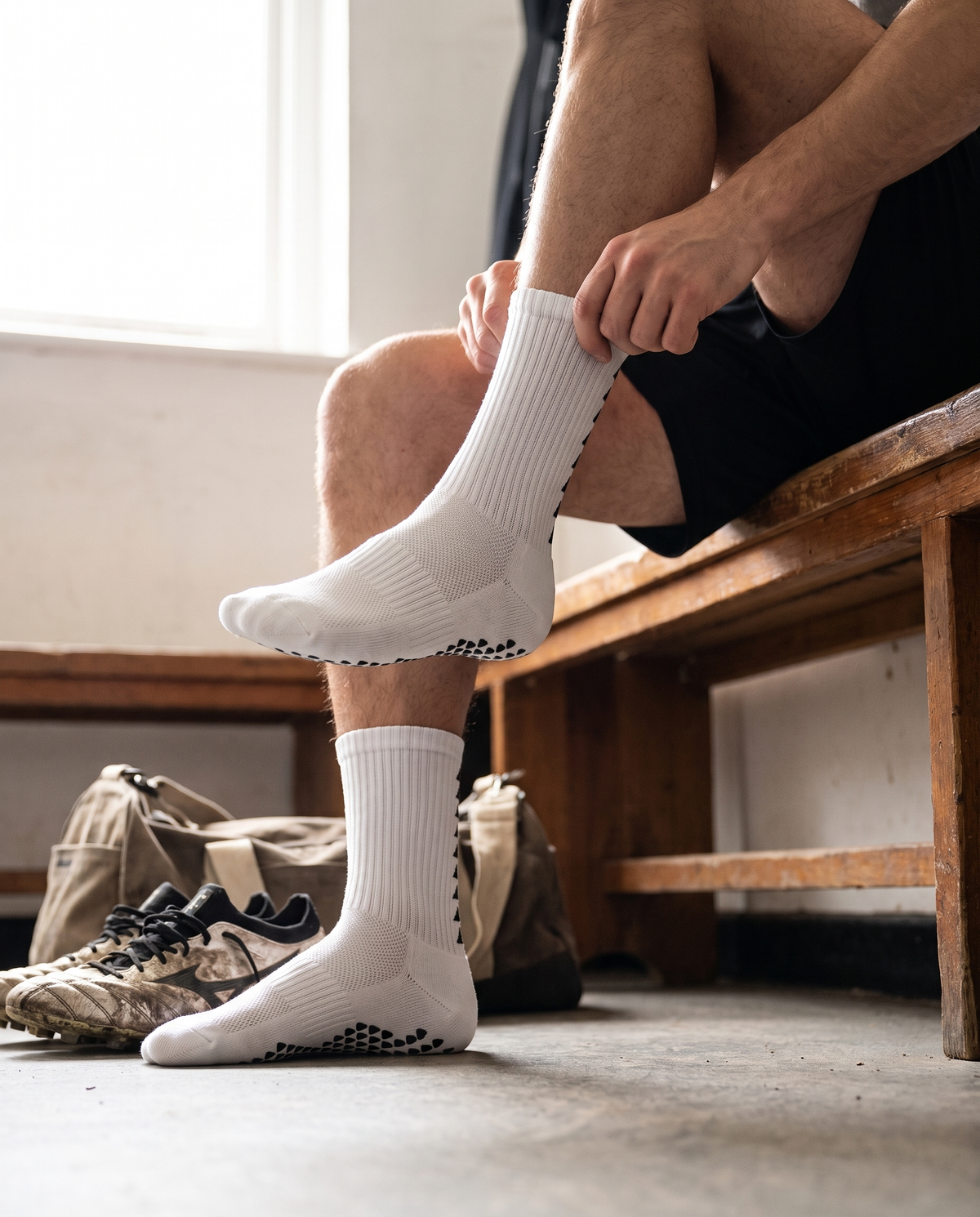 Player pulling on white Runegrip socks in a changing room